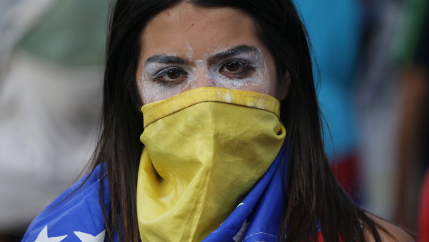 An anti-government protester covers her face with a Venezuelan flag.
