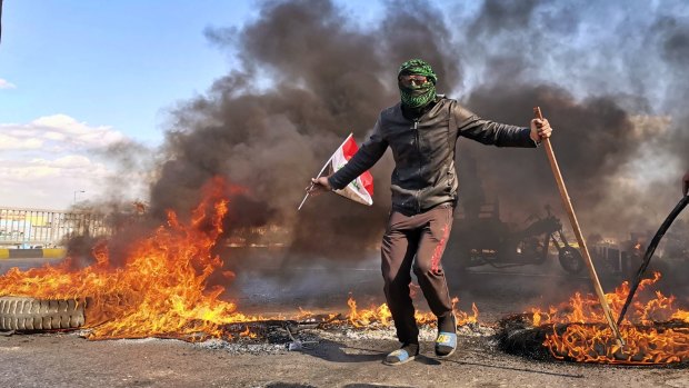 An anti-government protester stands near burning tires set fire to close a street during a demonstration against the newly appointed Prime Minister Mohammed Allawi in Najaf. 