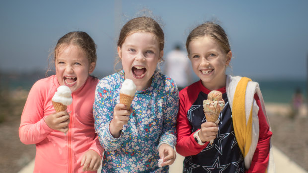 Seven-year-old friends Sofia, Eliza and Saffron share an ice-cream at Elwood beach. 
