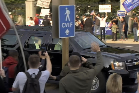 Trump waves as he drives past supporters. 