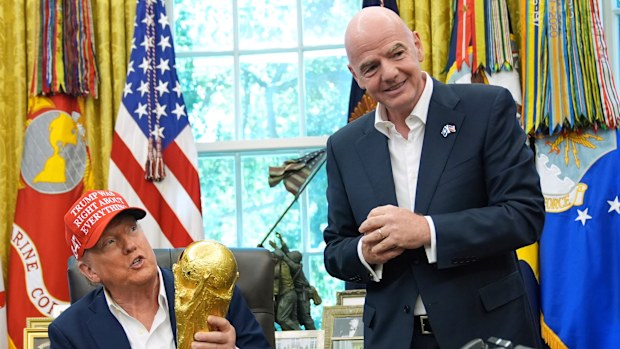 President Donald Trump holds the FIFA World Cup Winners Trophy as FIFA President Gianni Infantino looks on.