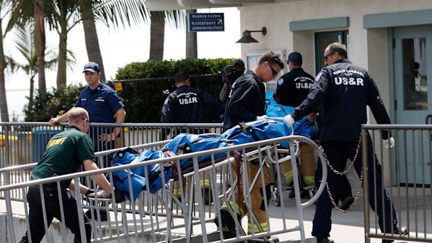 Santa Barbara City Search and Rescue and Santa Barbara Sheriff's officers move a recovered body onto the dock.