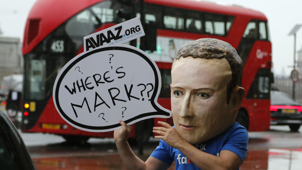 An activist wearing a Facebook CEO Mark Zuckerberg mask stands outside the meeting in Westminster.