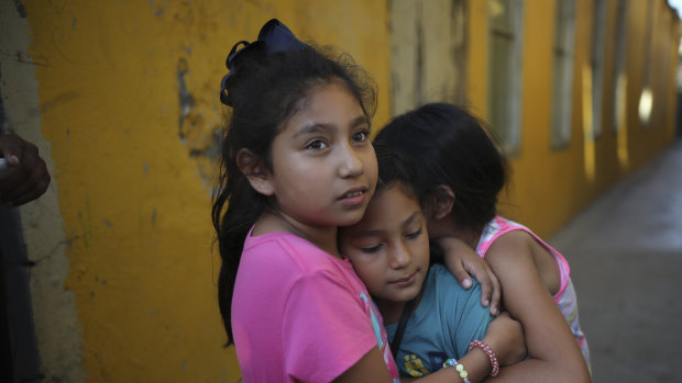 A Honduran girl, centre, is hugged by friends as she leaves a shelter after her family decided to accept voluntary return to Honduras, after spending nearly six months at the border, in Tijuana, Mexico, hoping to get to the US.