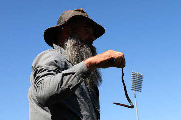 A snake catcher deals with the culprit who held up play in the AFLW on Saturday.