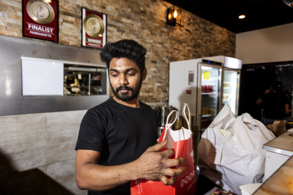 Srujan Gaddam from Dosa Hut Indian Restaurant in Harris Park handing over a delivery.