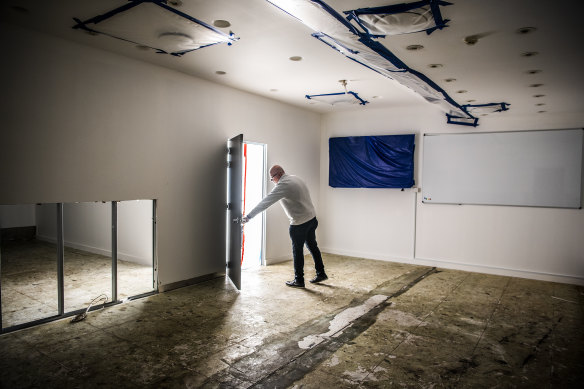 Business owner Chris Voukidis in an office where water is trickling down a shared wall from apartments above that caused a mould outbreak.