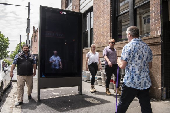 Pedestrians walk past a billboard outside the Colombian Hotel on Crown Street, Darlinghurst.