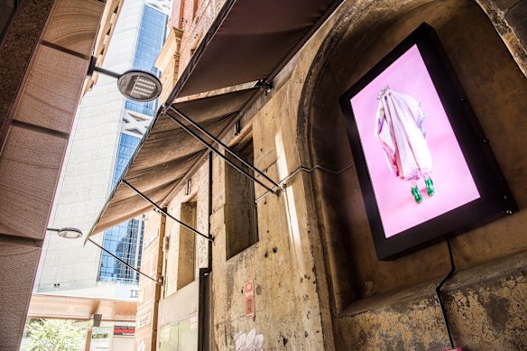 Plummer’s work, in which an interactive fortune-telling video installation on Abercrombie Lane features a pink furry ghost wearing a crown and snazzy green shoes. It has been temporarily removed. 