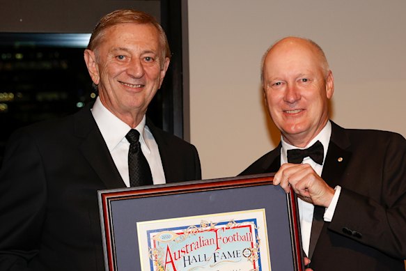 Australian Football Hall of Fame inductee Dennis Cometti accepts his certificate from league chairman Richard Goyder.
