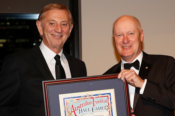 Australian Football Hall of Fame inductee Dennis Cometti accepts his certificate from then league chairman Richard Goyder.