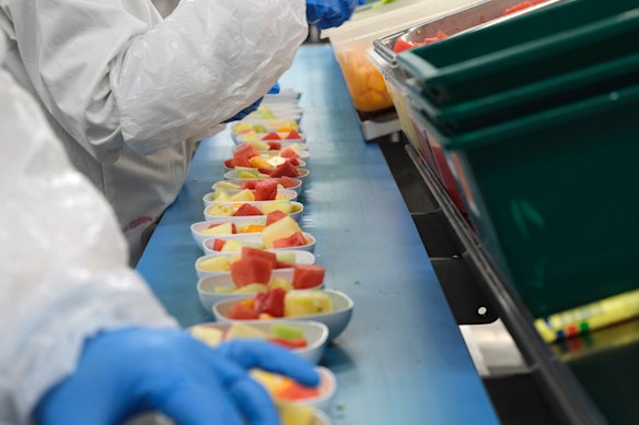 Preparing dishes of fruit salad.