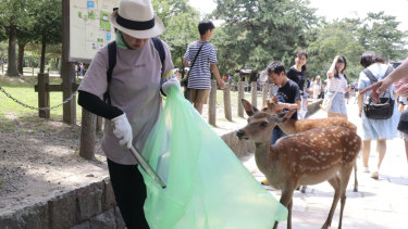 A volunteer picks up plastic rubbish during a clean-up campaign at Nara Park in western Japan on Wednesday.