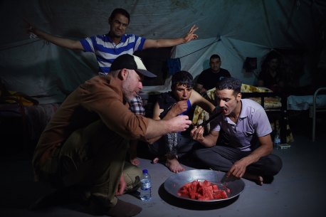 Michael Bachelard, left, eats watermelon off a dagger with Iraq’s Golden Division soldiers in their Mosul barracks on June 29, 2017.