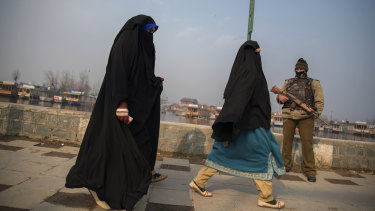 Kashmiri women walk past a soldier in Srinagar. 
