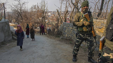 Young children walk past a paramilitary soldier in Kashmir, where India’s security crackdown is a familiar scene.
