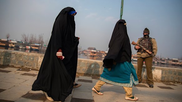 Kashmiri women walk past a soldier in Srinagar. 