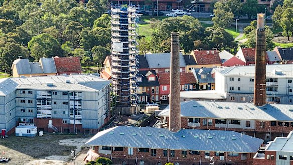 Scaffolding surrounds the crumbling heritage-listed chimney – owned by the developer – which has doubled insurance premiums for residents at the brickworks.