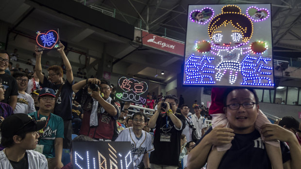Spectators hold up electronic signs during a baseball game between the Lamigo Monkeys and Fubon Guardians at the Taoyuan International Baseball Stadium in Taoyuan City, Taiwan.