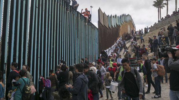Hundreds of migrants from Central America who travelled through Mexico gather with supporters at the border wall with the US where it ends at the Pacific Ocean, in Tijuana in April.