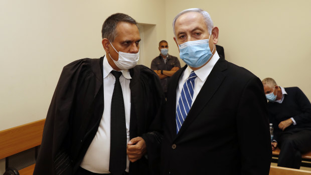Israeli Prime Minister Benjamin Netanyahu, wearing a face mask, stands inside the court room as his corruption trial opens at the Jerusalem District Court.