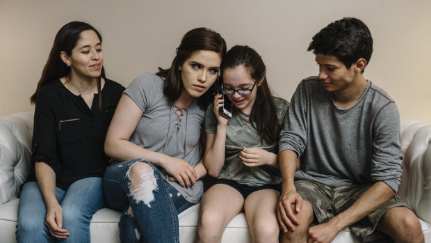 Yadira Lopez, left, looks on as her children (from left) Juana Barrios, Andrea Barrios and Oscar Barrios speak by phone with their father, who was detained by immigration authorities.