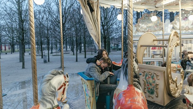 A couple ride the carousel, the only open attraction in the Tuileries park, in Paris.