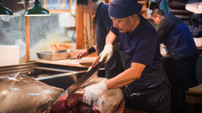 A wholesaler cuts a tuna at Tsukiji, the famed wholesale seafood market in Tokyo, on the day before its closure.