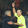 Match referee Mike Dean shows Tottenham manager Jose Mourinho a yellow card.