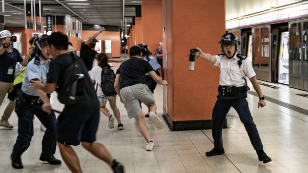 A police officer holds up pepper spray as he attempts to disperses protesters out of the platform at Po Lam Station.