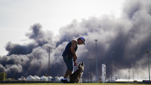 A man trains his dog with a cloud of smoke in the background from the TPC Group explosion in Port Neches, Texas. 