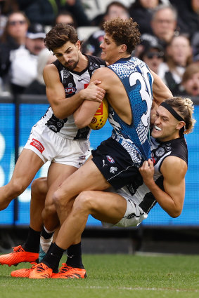 Carlton’s Charlie Curnow is tackled by Josh Daicos and Darcy Moore.