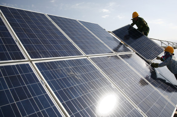 Workers install solar panels at a photovoltaic power station in Hami, Xinjiang.