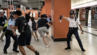A police officer holds up pepper spray as he attempts to disperses protesters out of the platform at Po Lam Station.