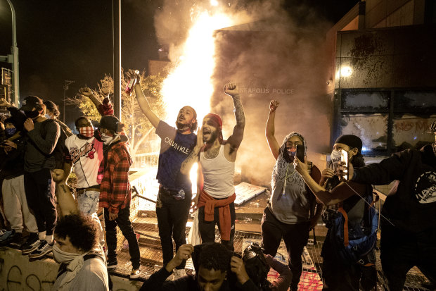 People stand outside the Minneapolis police 3rd Precinct building after fires were set at the building on Thursday, May 28, 2020, during demonstrations over the death George Floyd.