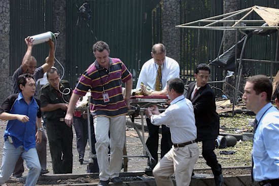 Grant Dooley (centre) helps carry embassy gardener Suryadi to an ambulance.