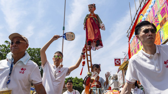 A child is hoisted up as participants take part in the Piu Sik Parade at the Bun Festival in Cheung Chau Island in Hong Kong.