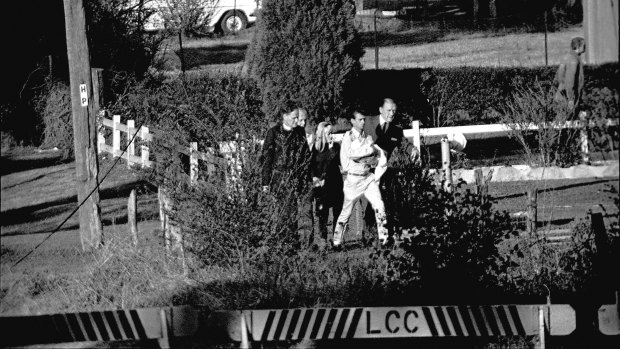 Wally and Beryl Mellish are escorted from their Glenfield home at the conclusion of the eight-day siege on July 10