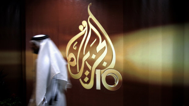 An employee of Al Jazeera Arabic language TV news channel walks past the broadcaster's logo in Doha, Qatar.