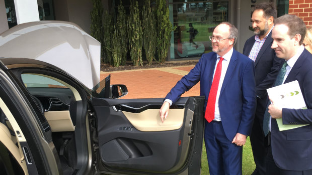 WA minister Bill Johnston inspects a Tesla vehicle powered by a lithium battery.