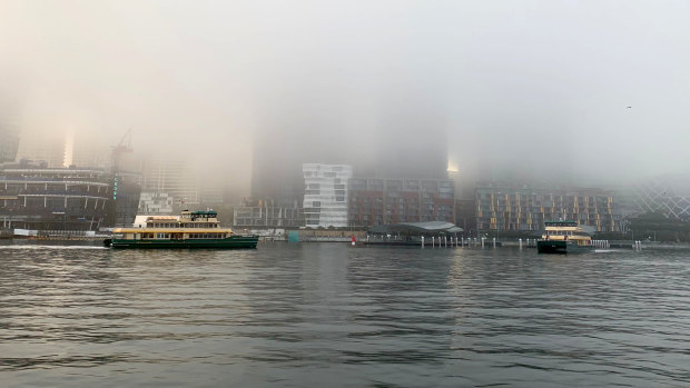 Fog blankets Barangaroo and Pyrmont Bay as ferries go past.