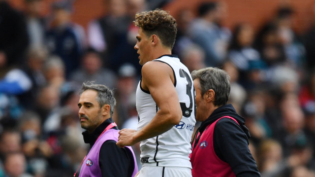 Charlie Curnow is helped from the field.