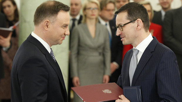 Polish President Andrzej Duda, left, hands Prime Minister Mateusz Morawiecki the document of his appointment last December.