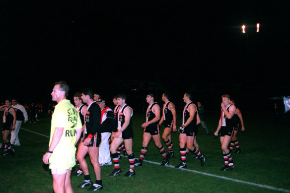 Players stand in the dark at Waverley Park. 