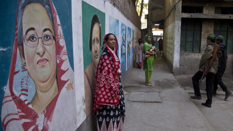 A women stands next to a mural displaying a portrait of Bangladesh's Prime Minister Sheikh Hasina at a polling station in Dhaka on Sunday.