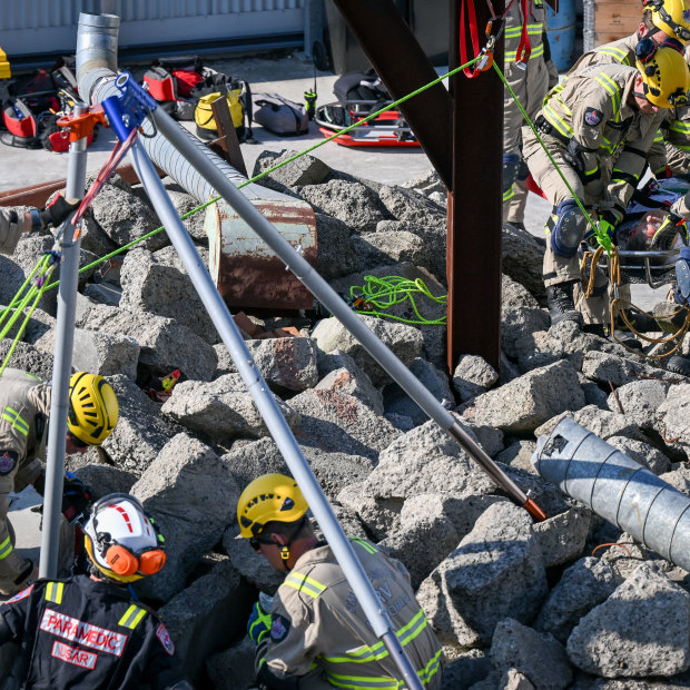 Firefighting crews winch people out of the rubble using a portable crane.
