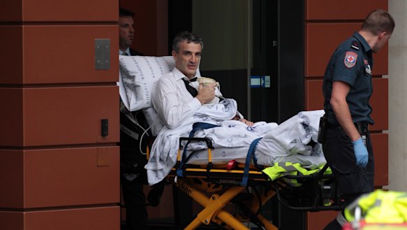 Terry McMaster leaves the Federal Court with the aid of paramedics after collapsing while being questioned.