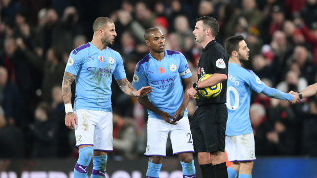 Manchester City players speak to match referee Michael Oliver.