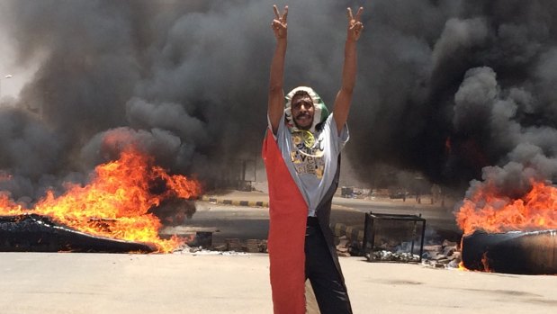 A protester stands in front of burning debris near Khartoum's army headquarters, in Khartoum, on Monday.