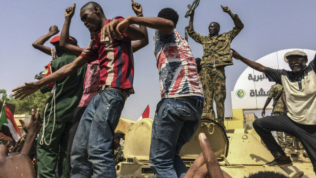 Sudanese men celebrate in April after officials said the military had forced longtime autocratic President Omar al-Bashir to step down.